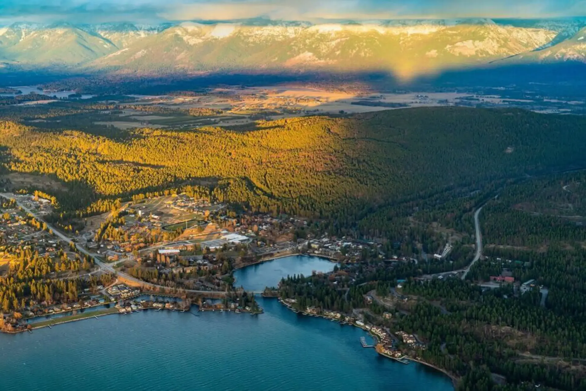 Aerial view of Bigfork, Montana at the edge of Flathead Lake with the Swan River bay and snow-capped Swan Mountains at sunset