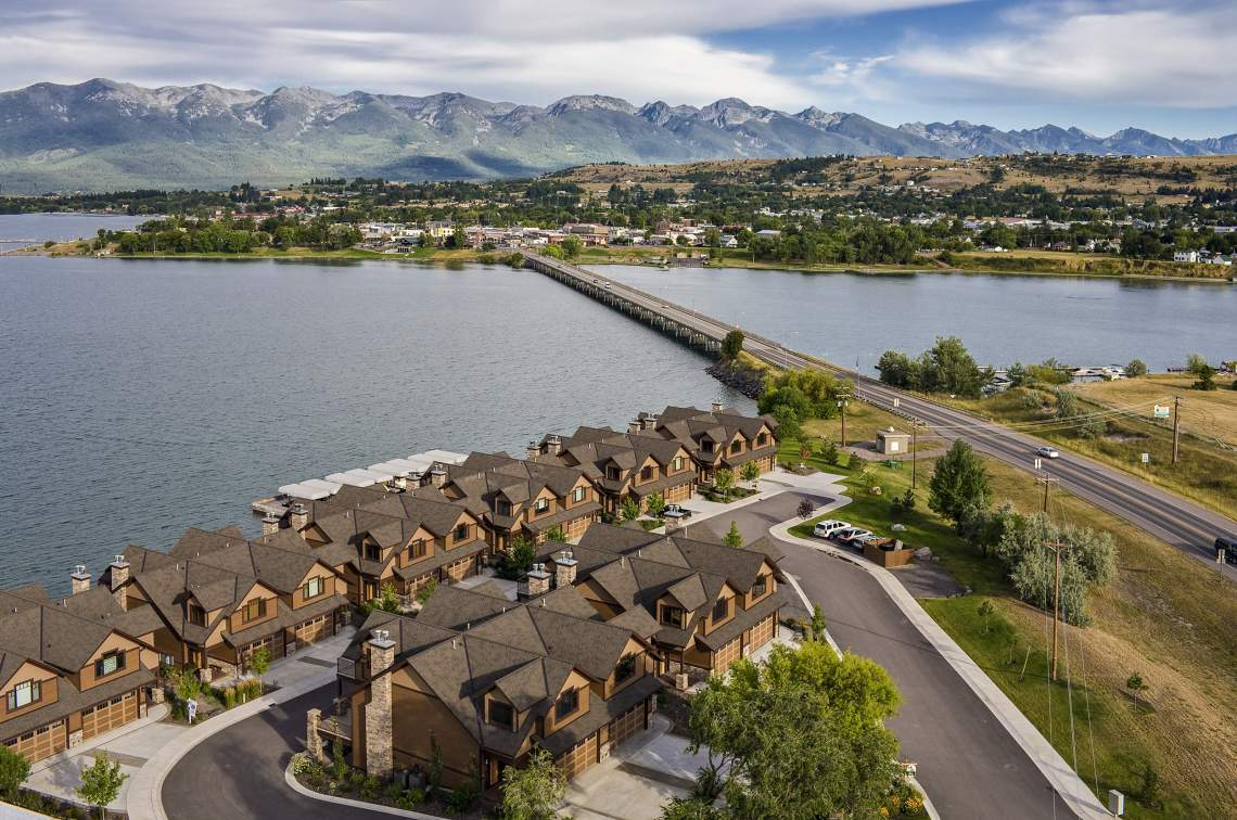 Aerial view of Polson, Montana on Flathead Lake with the bridge, lakeside homes, and the Mission Mountains in the distance