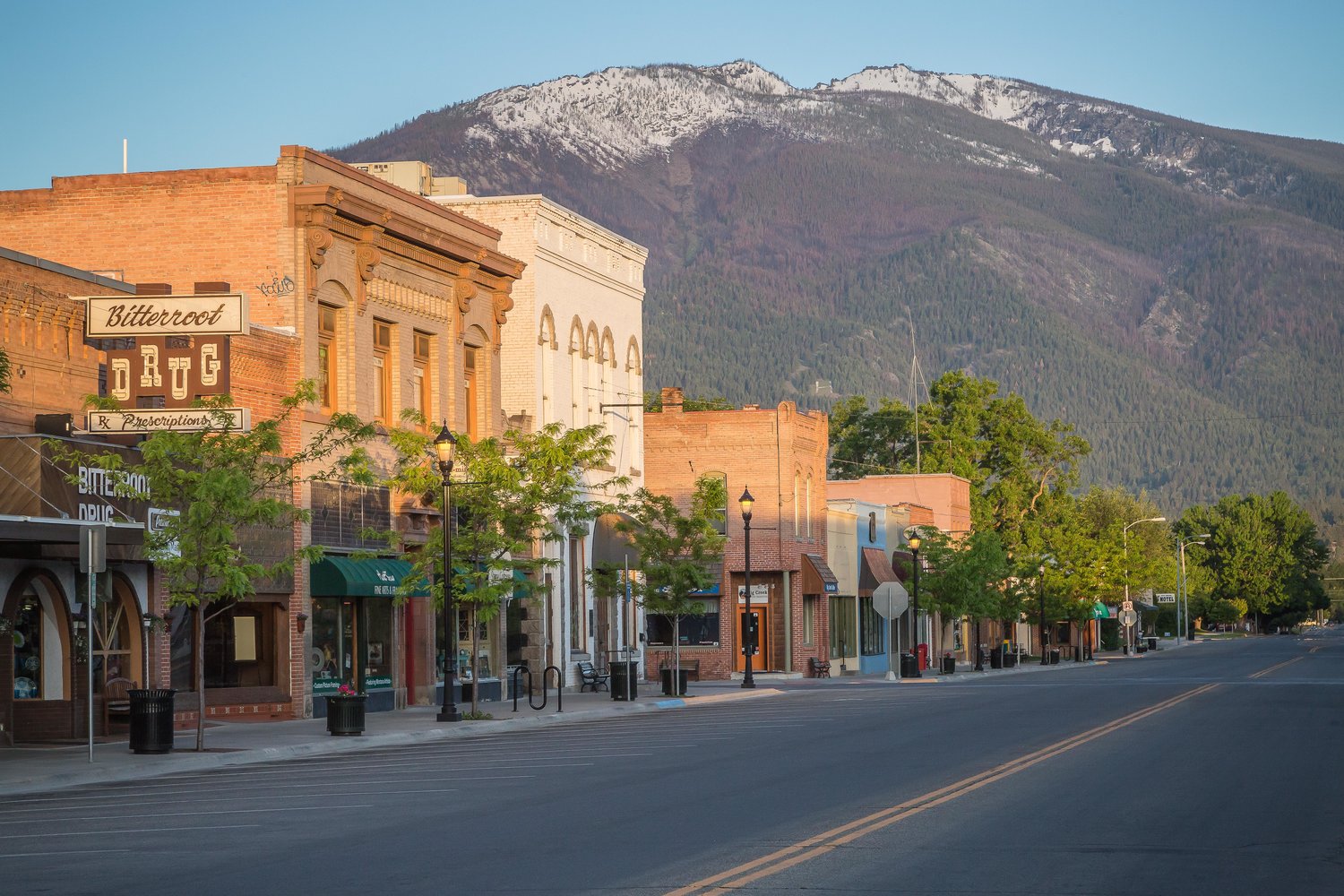 Historic brick storefronts on Main Street in Hamilton, Montana beneath the snow-capped Bitterroot Mountains